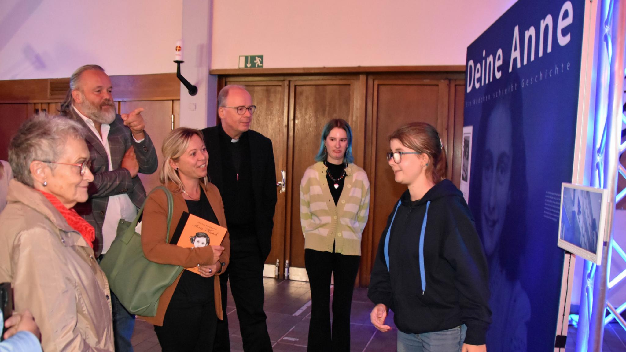 Eine Jugendliche führt Besucher - darunter Staatssekretärin Jessica Heide und Bischof Ackermann - durch die Ausstellung.