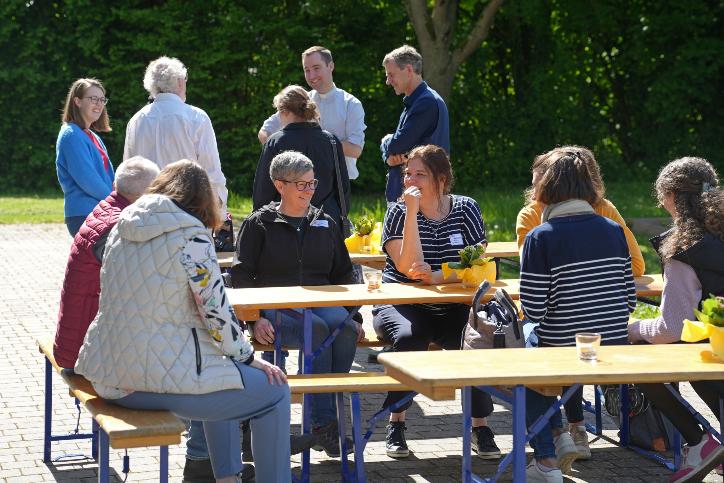 Synodalversammlung_2024 mit Menschen im Gespräch in der Sonne stehend und sitzend