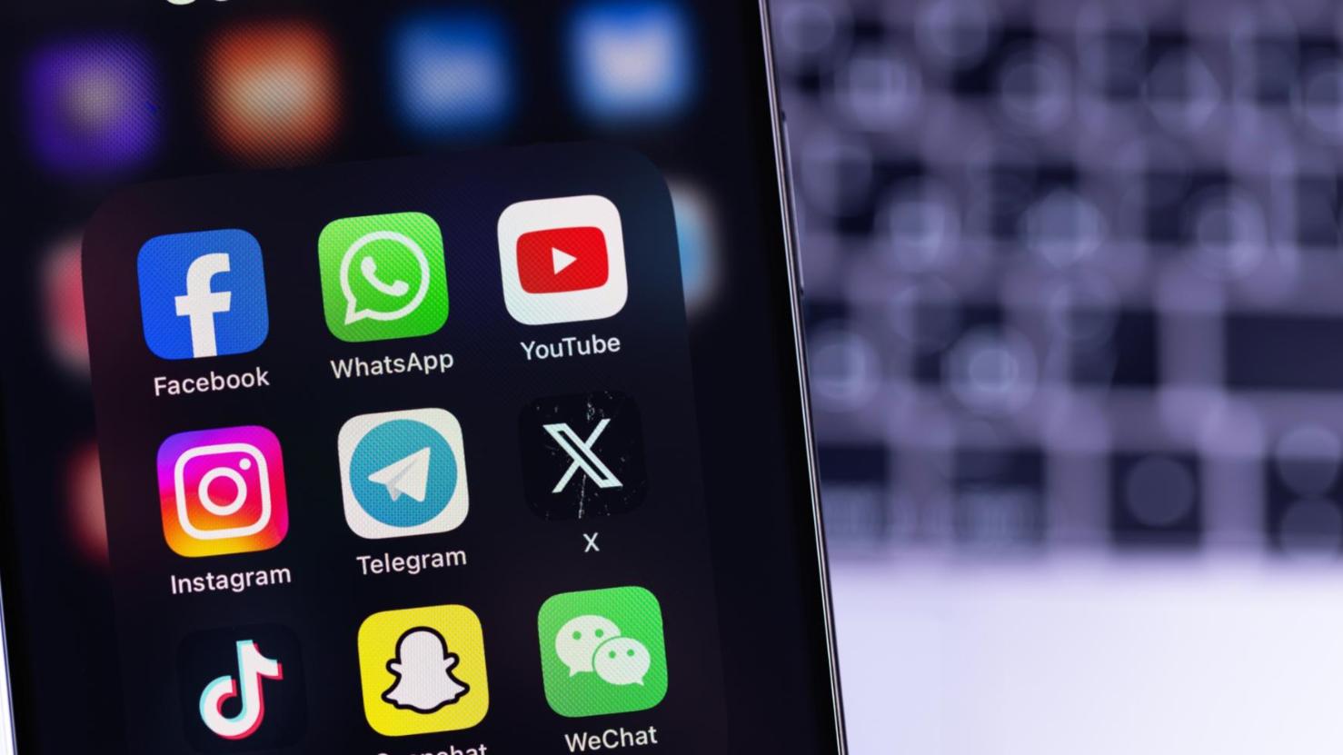 Bild von Handy mit Apps vor verschwommener Tastatur